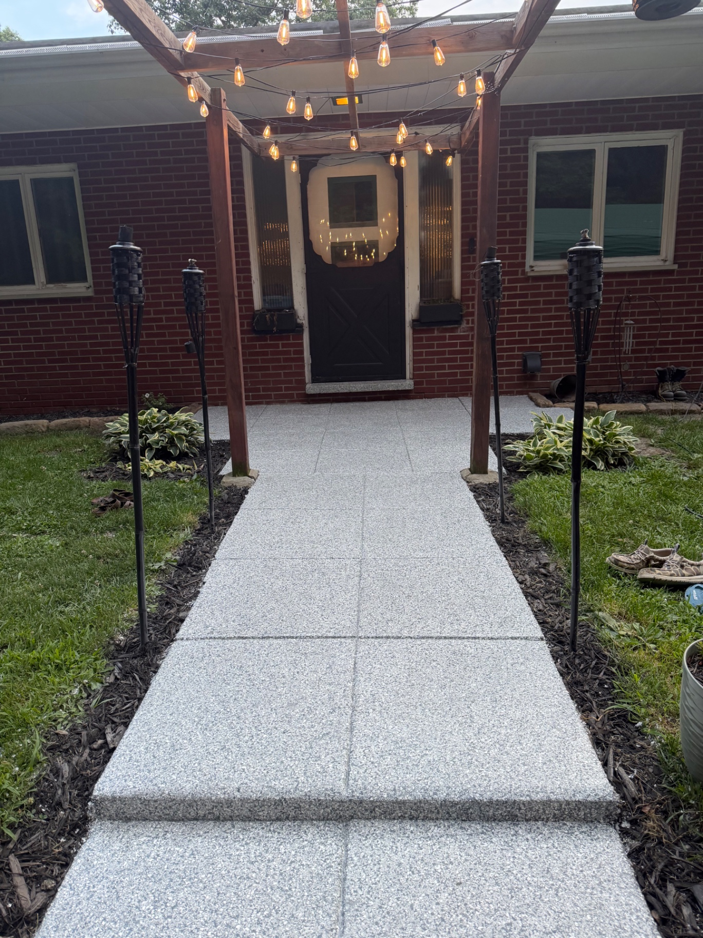 Finished flake-coated concrete walkway leading to a brick home's entry
